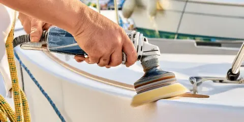 Hand poliert mit Maschine den weißen Bootsrumpf. Glänzende Oberflächen entstehen beim Boot polieren.