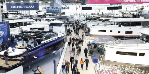 Besucher bestaunen Yachten auf einer Messe. Ein glänzendes, blaues Boot im Vordergrund erinnert an eine Fahrt auf dem kanal frankreich.