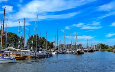 Segelboote im Enkhuizen Hafen unter blauem Himmel mit weißen Wolken.