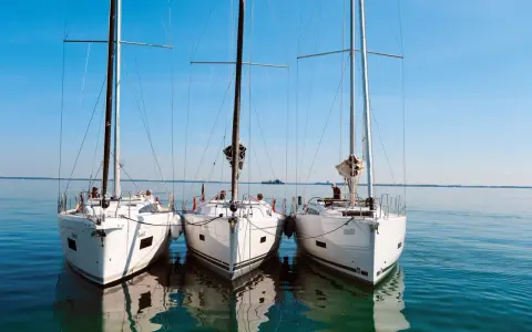 Drei weiße Segelyachten liegen nebeneinander im ruhigen Wasser. Ein Blick auf die elegante Bauweise, wie sie nur ein renommierter segelyacht hersteller hervorbringen kann.