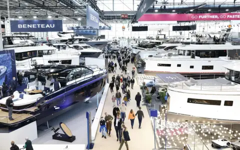 Besucher bestaunen Yachten auf einer Messe. Ein glänzendes, blaues Boot im Vordergrund erinnert an eine Fahrt auf dem kanal frankreich.