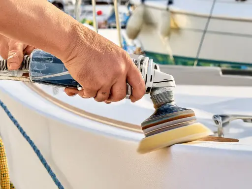 Hand poliert mit Maschine den weißen Bootsrumpf. Glänzende Oberflächen entstehen beim Boot polieren.