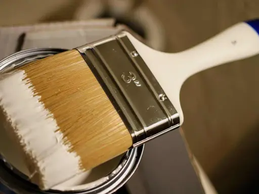 Pinsel mit weißer Farbe, bereit, ein Holzboot zu lackieren.
