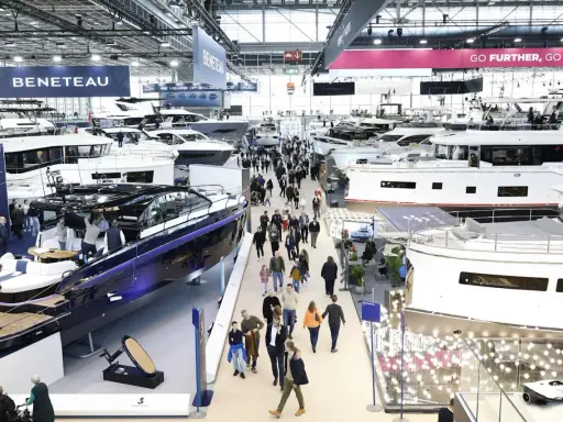 Besucher bestaunen Yachten auf einer Messe. Ein glänzendes, blaues Boot im Vordergrund erinnert an eine Fahrt auf dem kanal frankreich.