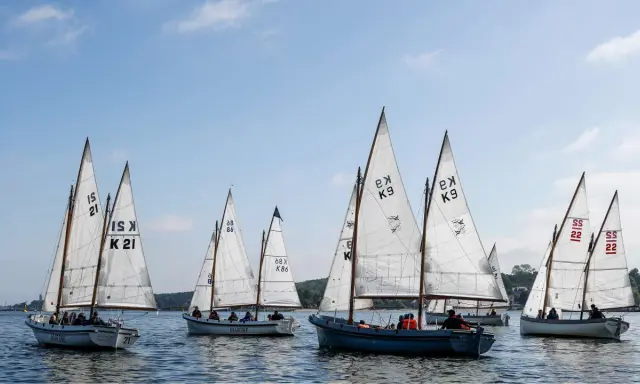 Segelboote mit weißen Segeln und Nummern wie "21" und "K9" auf dem Wasser, ein Teil der Veranstaltung "wm kiel".