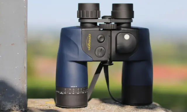 Ein blaues Omegon Fernglas 7x50, dessen Bedeutung in der Vergrößerung und Objektivgröße liegt, steht auf einem Stein.