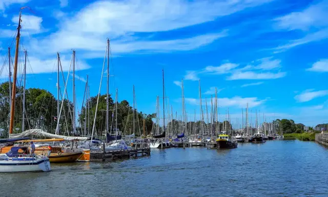 Segelboote im Enkhuizen Hafen unter blauem Himmel mit weißen Wolken.
