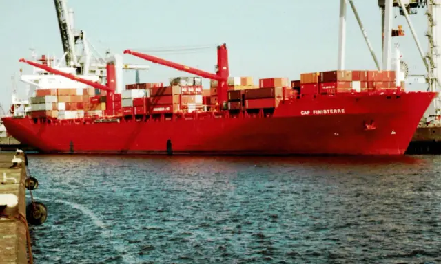 Rotes Containerschiff "Cap Finisterre" im Hafen, beladen mit vielen Containern, Kräne im Hintergrund.