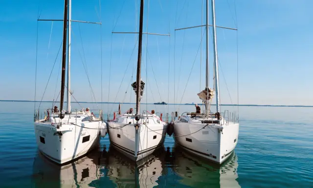 Drei weiße Segelyachten liegen nebeneinander im ruhigen Wasser. Ein Blick auf die elegante Bauweise, wie sie nur ein renommierter segelyacht hersteller hervorbringen kann.