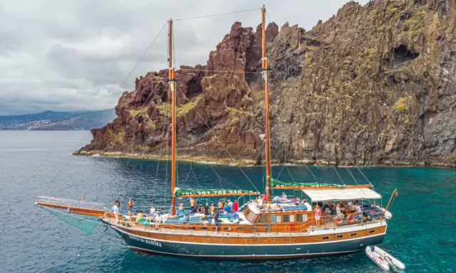 Segelschiff mit vielen Passagieren vor steiler Felsküste, ein Traum für Madeira Segeln.