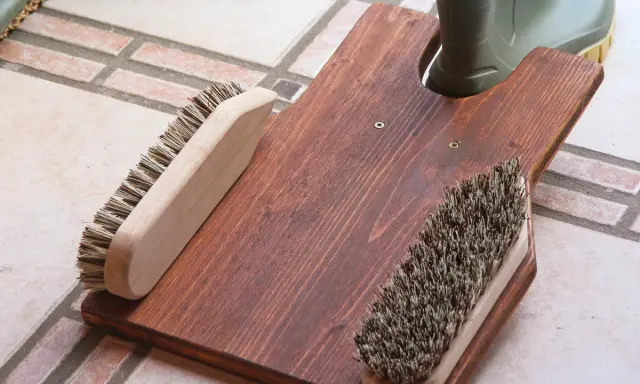 Selbstgebauter Bootsanker aus Holz mit zwei Bürsten und einem grünen Stiefel.