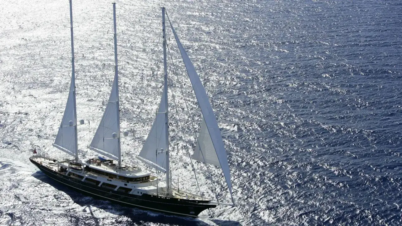 Gro&szlig;es Segelschiff mit wei&szlig;en Segeln auf glitzerndem Meer. Ein Traum von Luxus und Freiheit, wie ein Schluck pink gin vi.