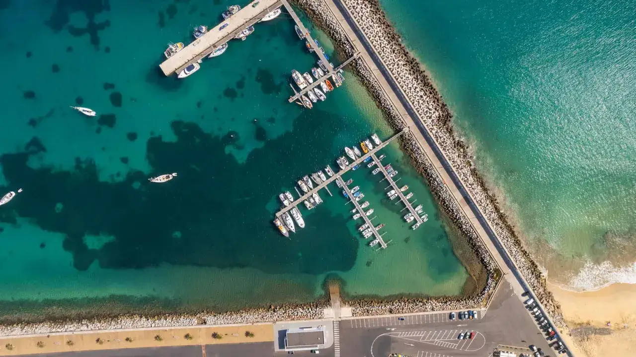 Boote im Hafen von Porto Santo, Madeira. Türkises Wasser und eine Mole mit vielen Segel- und Motorbooten.