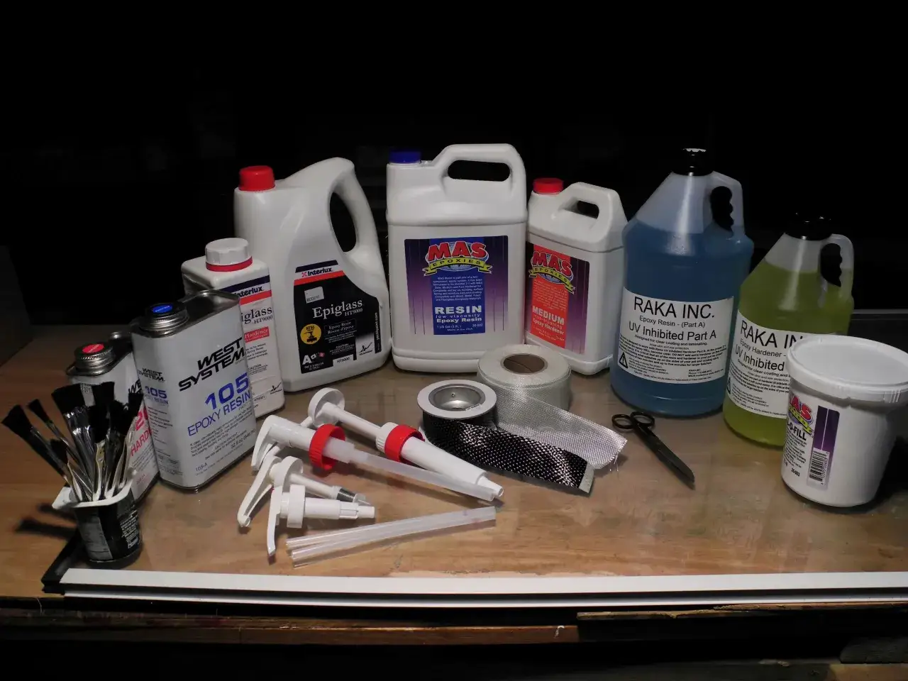 Verschiedene Beh&auml;lter mit Epoxidharz und H&auml;rter, Pinsel, Schere und Gewebe f&uuml;r Reparaturen.
