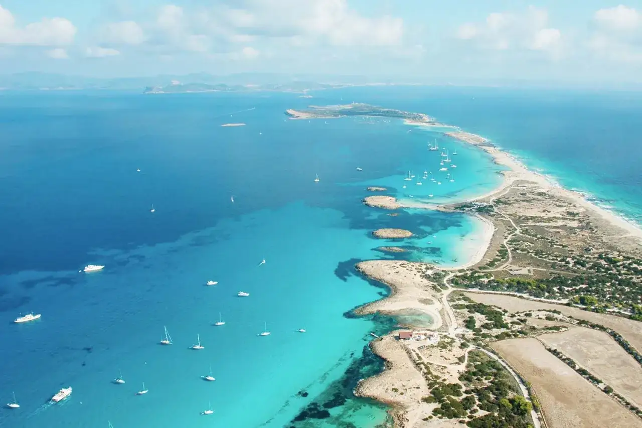 Traumhafte Küstenlinie von Formentera, Ibiza. Türkisblaues Wasser, weiße Sandstrände und zahlreiche Segelboote.