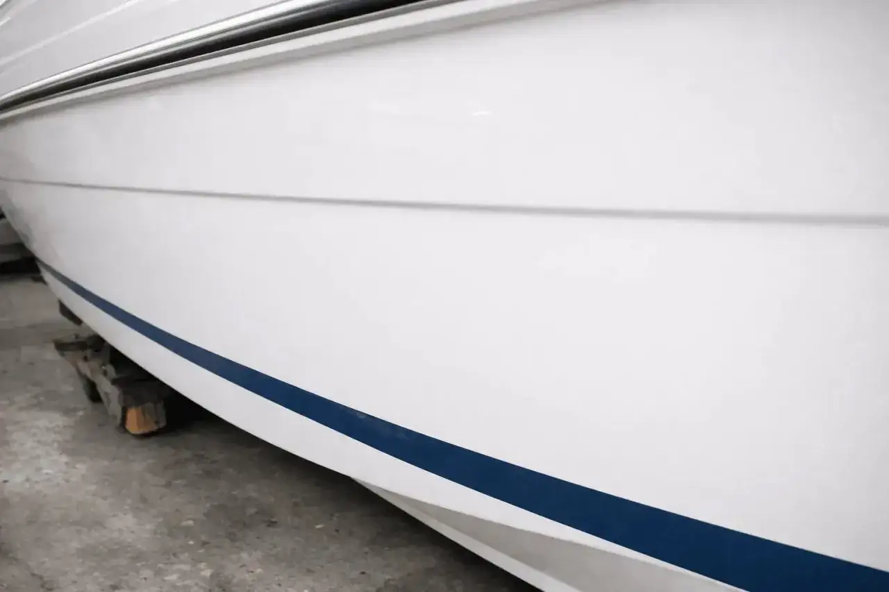 Detailaufnahme eines wei&szlig;en Bootes mit blauer Zierlinie, bereit f&uuml;r das Boot polieren.