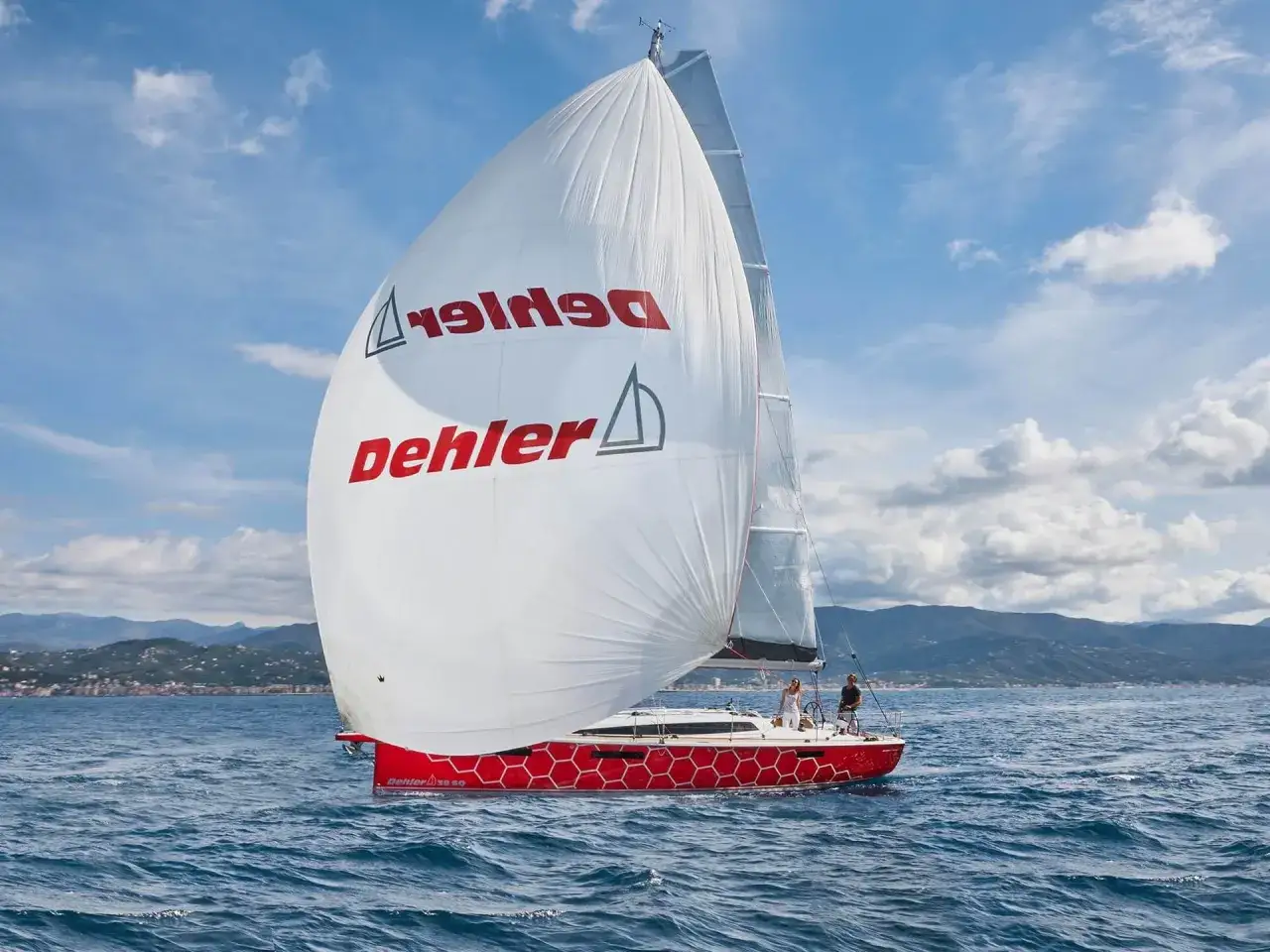 Segelboot Dehler 31 mit roten Wabenmuster am Rumpf, segelt auf blauem Meer. Technische Daten sind auf dem Segel zu sehen.