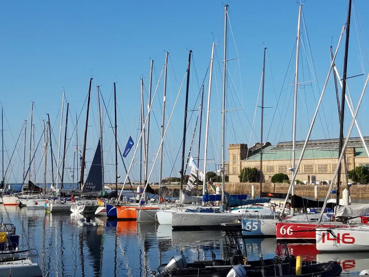 Segelboote im Hafen, bereit für das Fastnet Race. Boote mit Nummern wie 65, 66 und 146 liegen im Wasser.