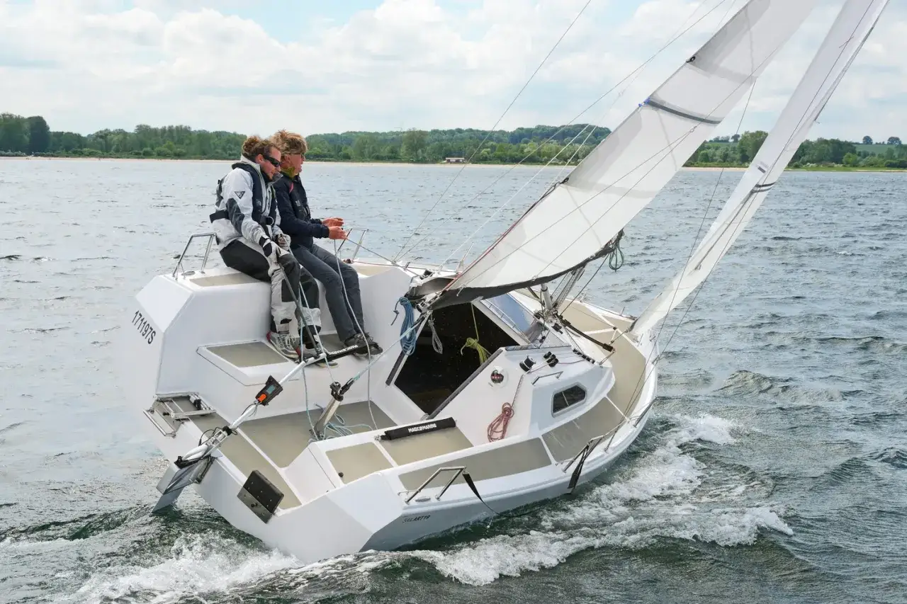 Zwei Segler genießen eine Fahrt auf der sailart 19. Das Boot gleitet durch das Wasser, die Segel sind gesetzt.
