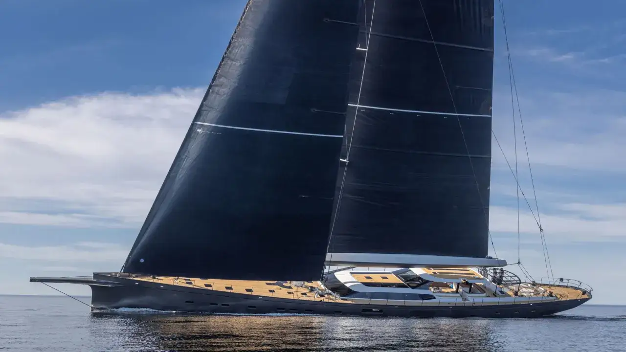 Eine elegante Segelyacht mit schwarzen Segeln gleitet &uuml;ber ruhiges Wasser. Die pink gin vi ist ein Traum auf See.