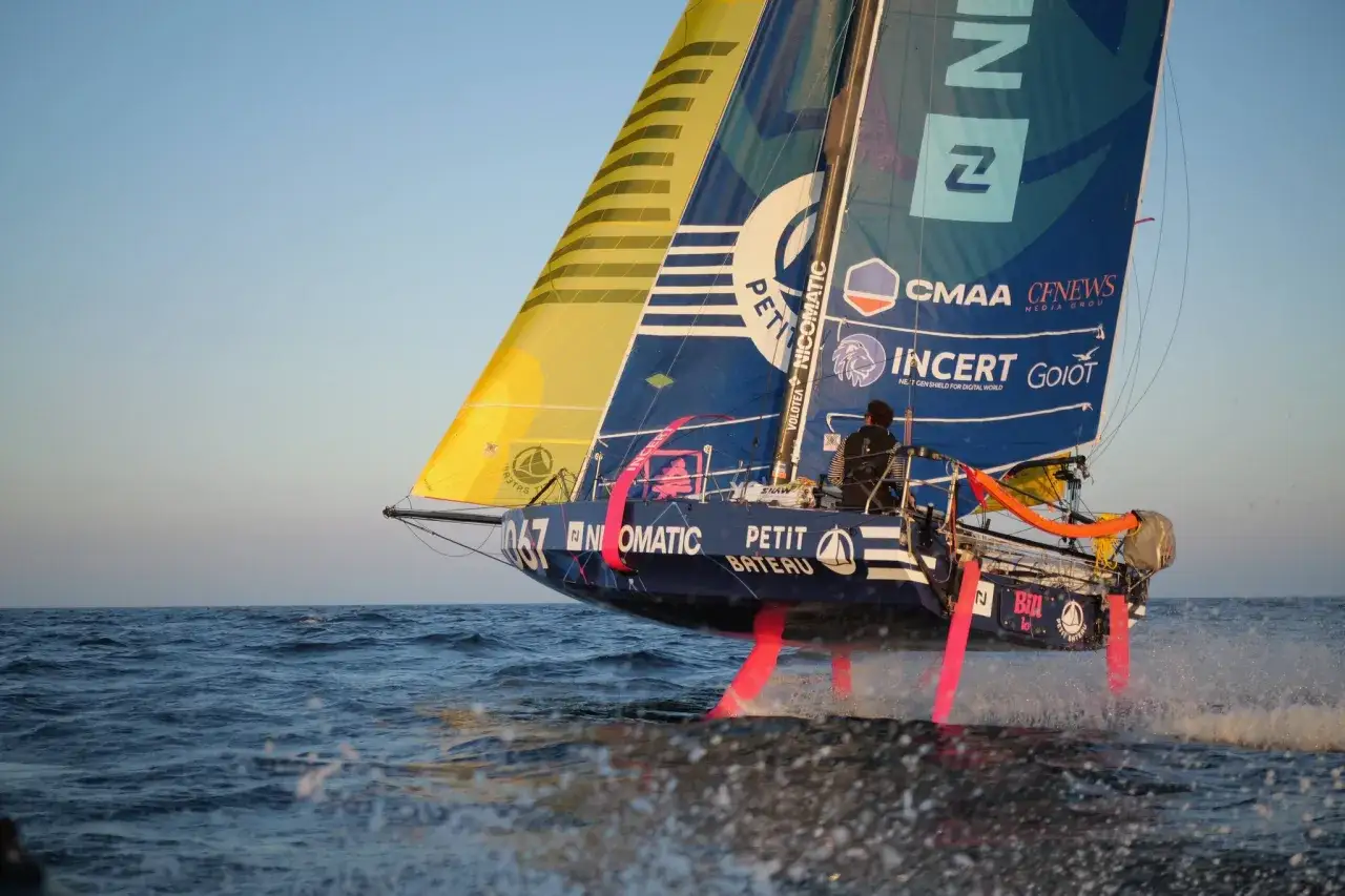 Segelboot mit pinken Foils rast &uuml;ber das Meer, bereit f&uuml;r die Mini Transat.