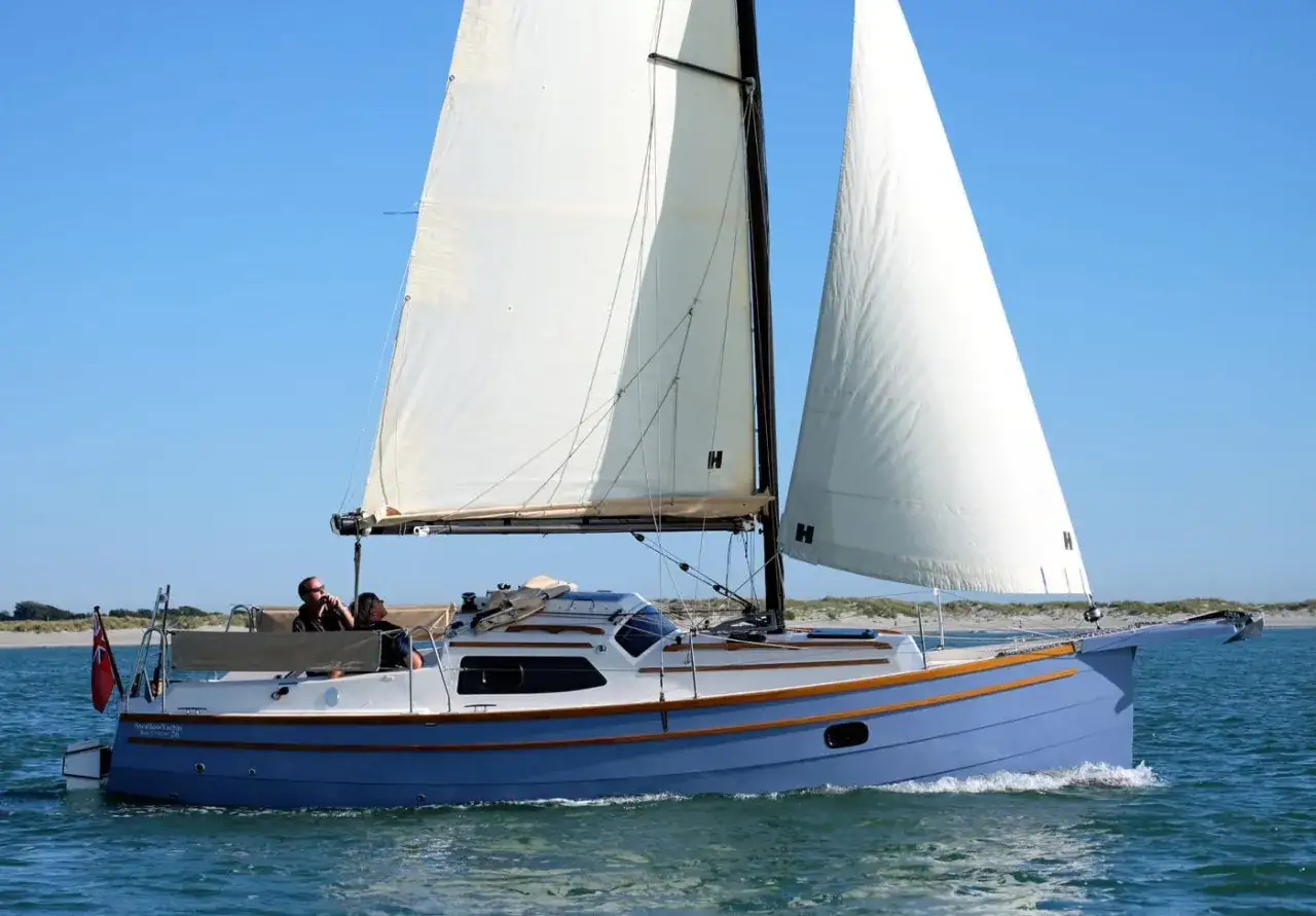 Eine blaue Baycruiser 26 segelt auf dem Meer, zwei Personen an Bord genie&szlig;en die Fahrt.