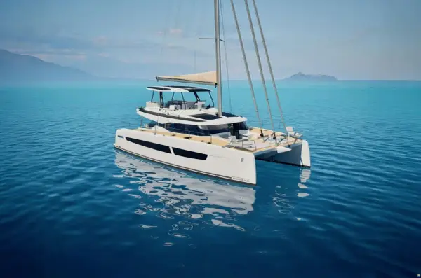 Eine weiße Katamaran-Yacht, eine FOUNTAINE PAJOT, gleitet auf ruhigem, blauem Wasser. Im Hintergrund sind Berge und eine Insel zu sehen.