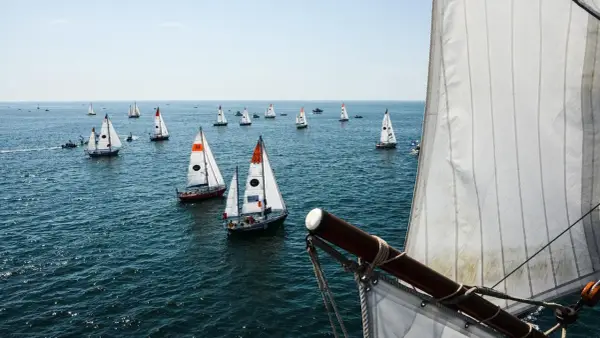 Viele Segelboote auf dem Meer, ein Teil der Segel im Vordergrund. Ein spannender Moment der Golden Globe Race.