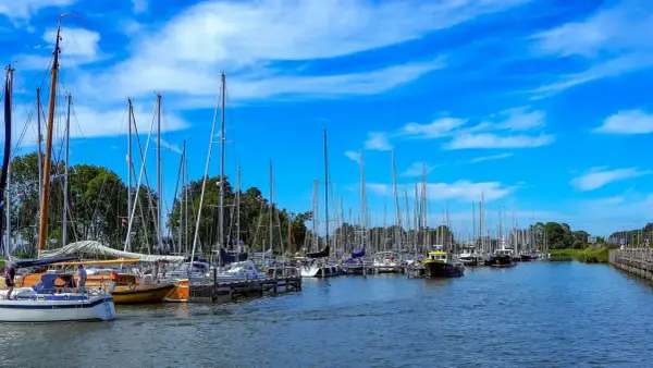 Segelboote im Enkhuizen Hafen unter blauem Himmel mit weißen Wolken.