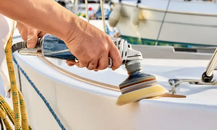Hand poliert mit Maschine den weißen Bootsrumpf. Glänzende Oberflächen entstehen beim Boot polieren.